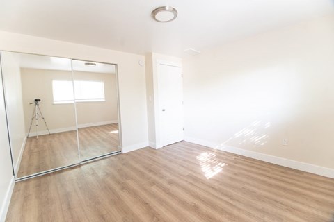 A room with a large mirror and wooden flooring.