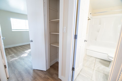 A white door is open to a room with a white bathtub.