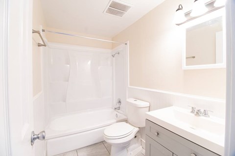 A white bathroom with a toilet, sink, and bathtub.
