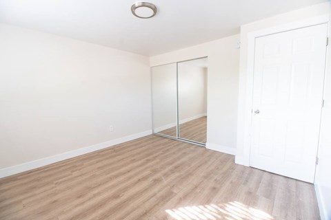 A room with a white door and a mirror on the wall.