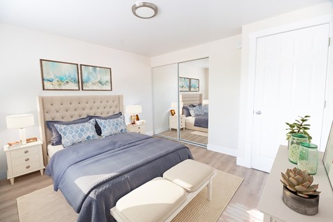 A bedroom with a large bed and a mirror on the wall.