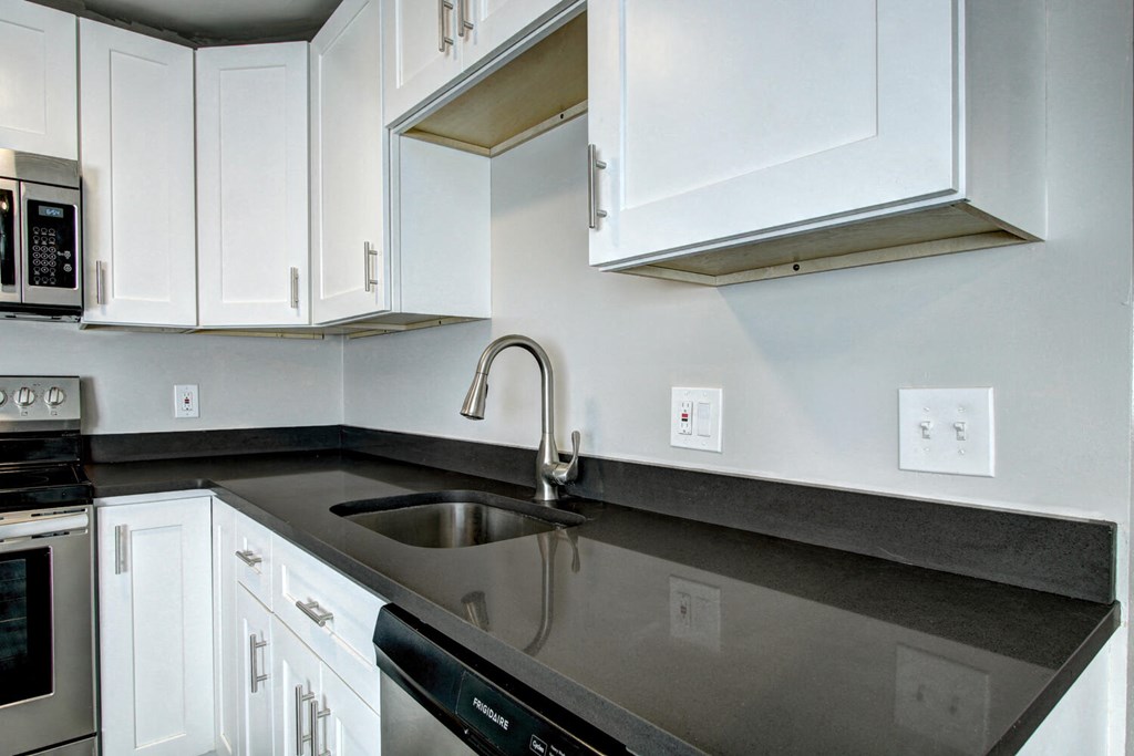 a kitchen with white cabinets and black countertops