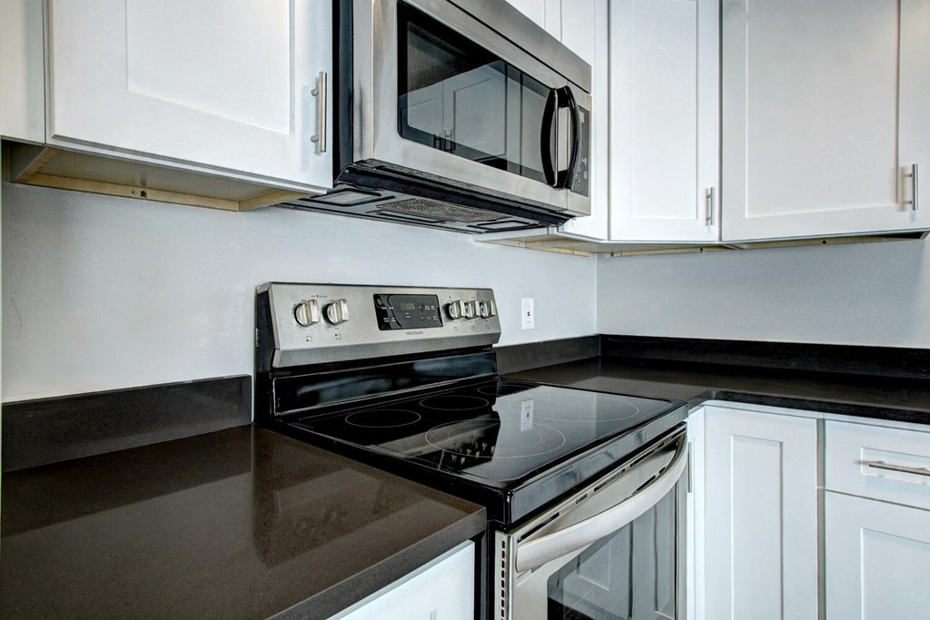 a kitchen with white cabinets and black countertops