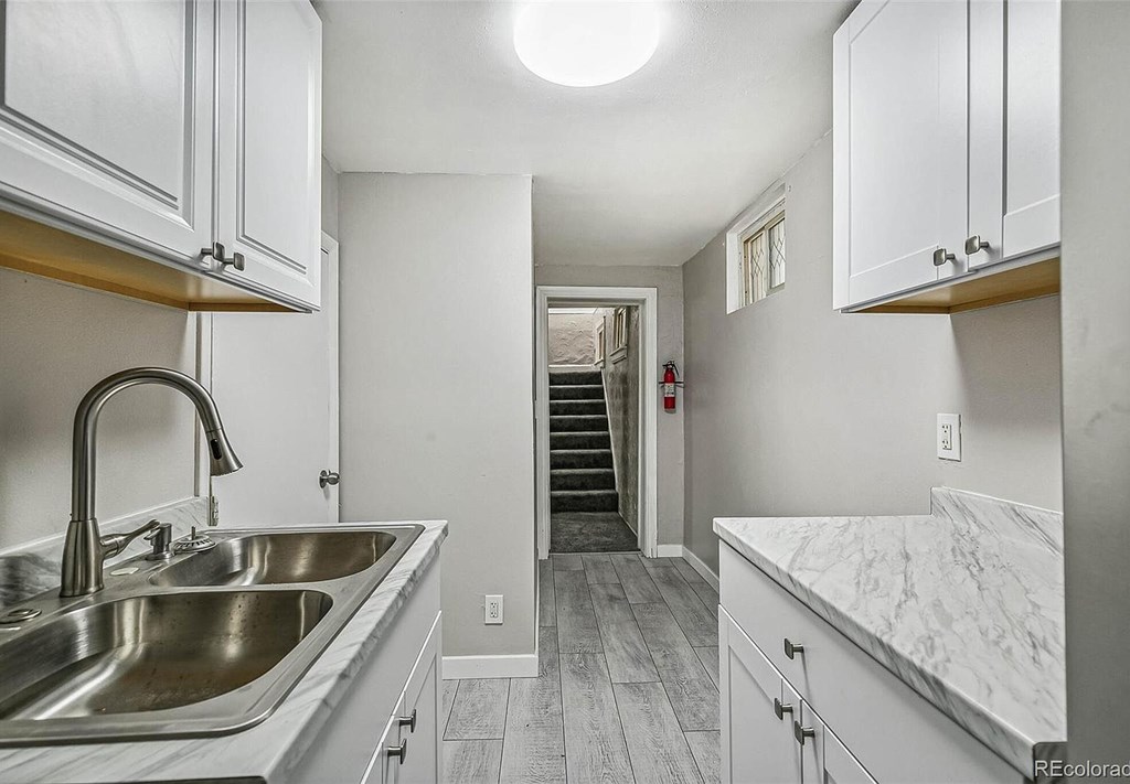 A kitchen with a marble counter top and stainless steel sink.