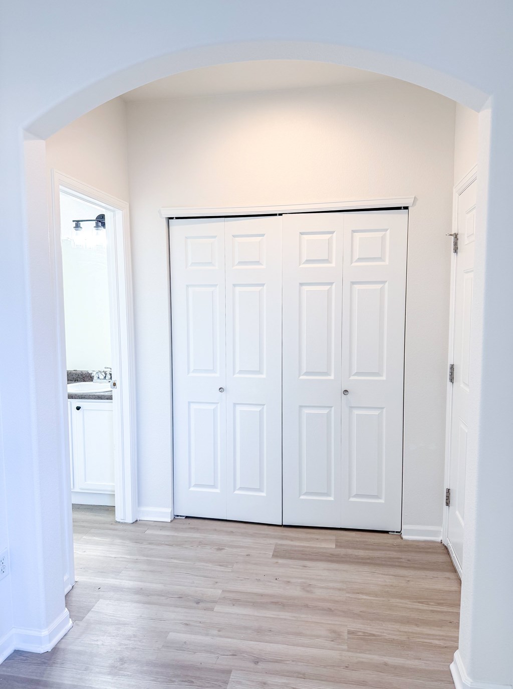 A white double door is in a white archway.