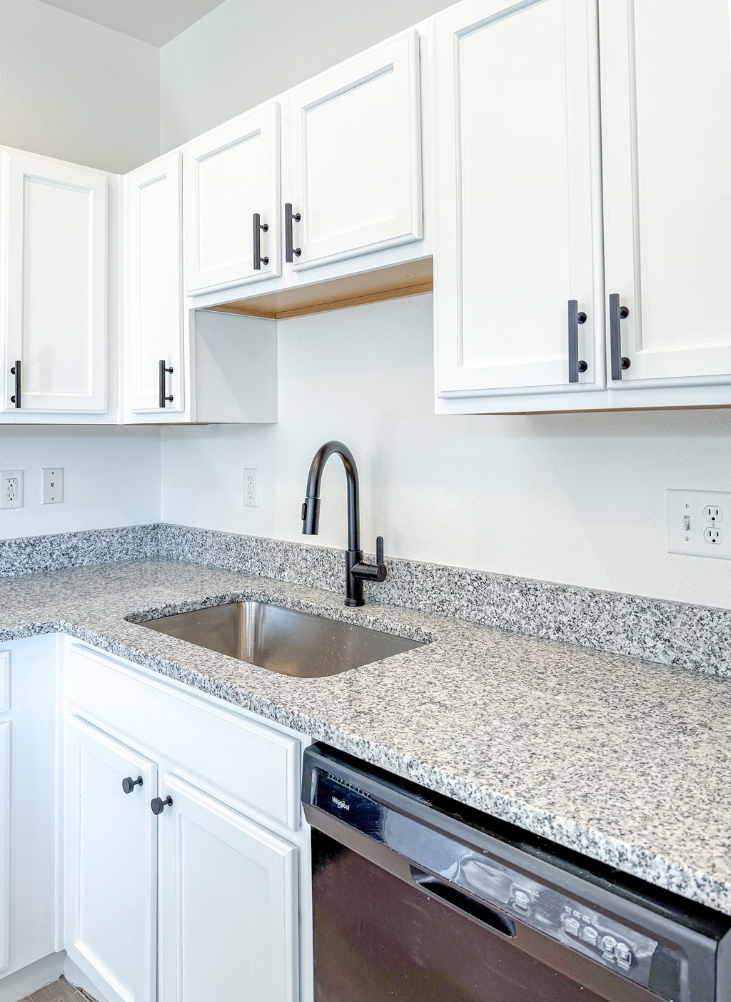A kitchen with white cabinets and a granite countertop.