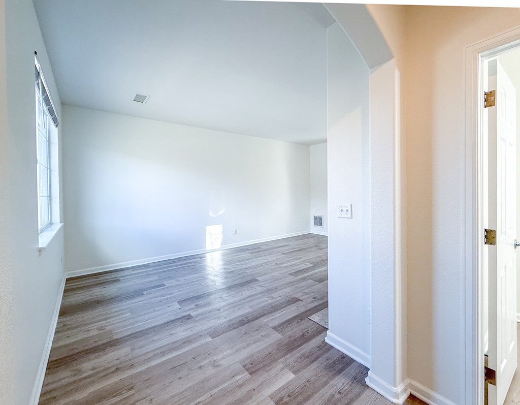 A room with wooden flooring and white walls.