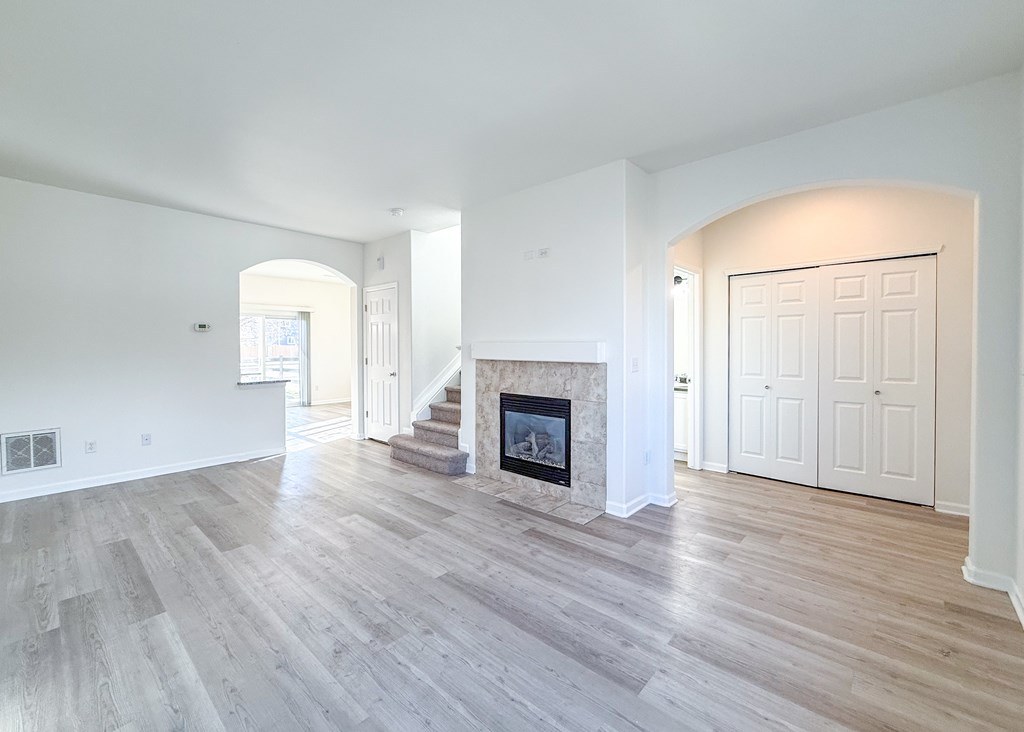 A spacious living room with a fireplace and hardwood floors.