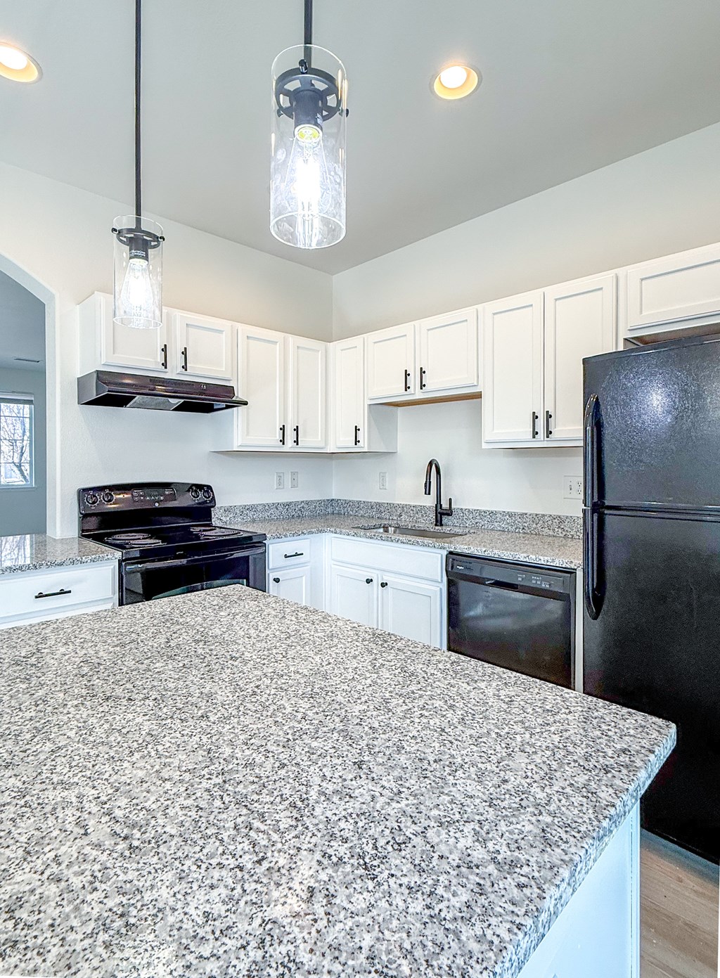 A kitchen with granite countertops and white cabinets.