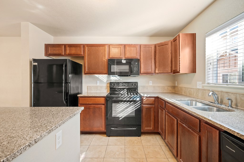 A kitchen with black appliances and brown cabinets.