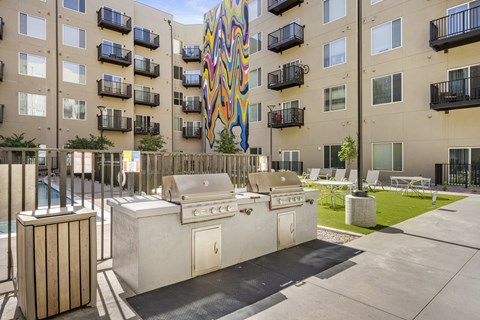A colorful mural on a building behind a patio with a grill and a hot tub.