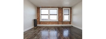 an empty room with a brick wall and two windows