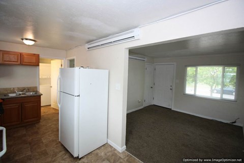 A white refrigerator in a kitchen with brown flooring.