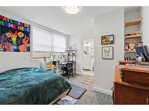 A bedroom with a bed, desk, and a poster on the wall.