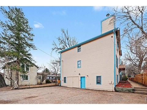 A white and blue building with a blue door and a small porch.