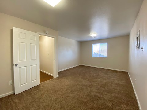 A room with a carpeted floor and a door leading to another room.