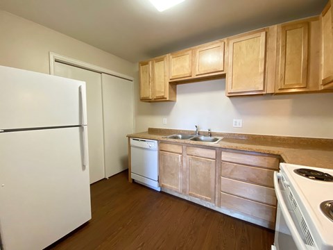 A kitchen with a white refrigerator, wooden cabinets, and a white stove top oven.