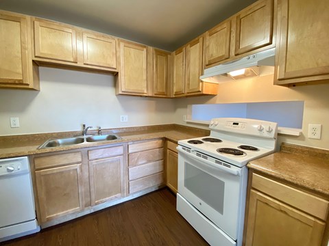 A kitchen with a white stove and wooden cabinets.