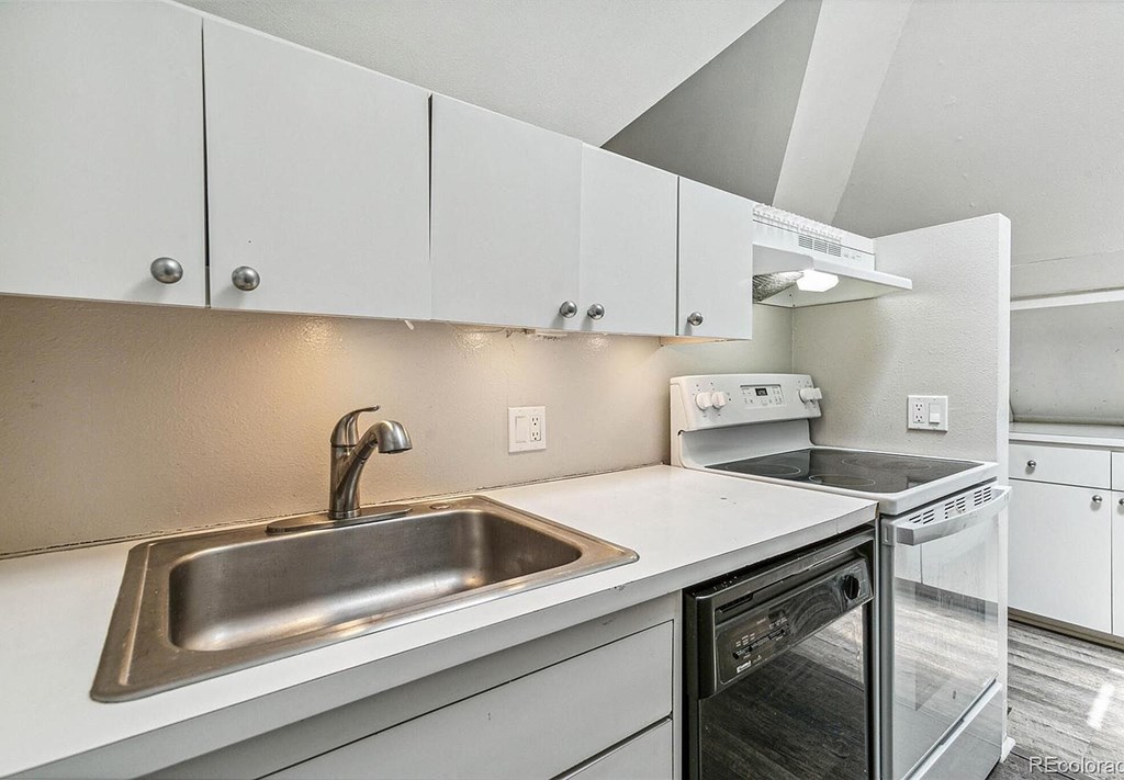 A kitchen with a stainless steel sink and white cabinets.