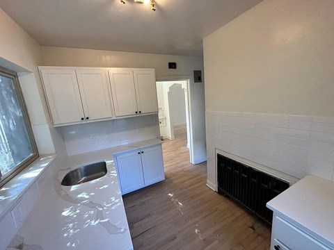 a view of a kitchen with white cabinets and a fireplace