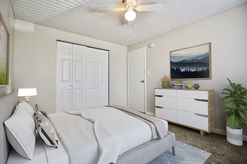 A bedroom with a bed, nightstand, and a painting on the wall.