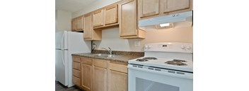 A kitchen with a white stove and wooden cabinets.