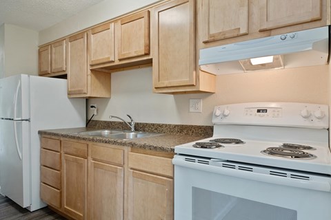A kitchen with a white stove and wooden cabinets.