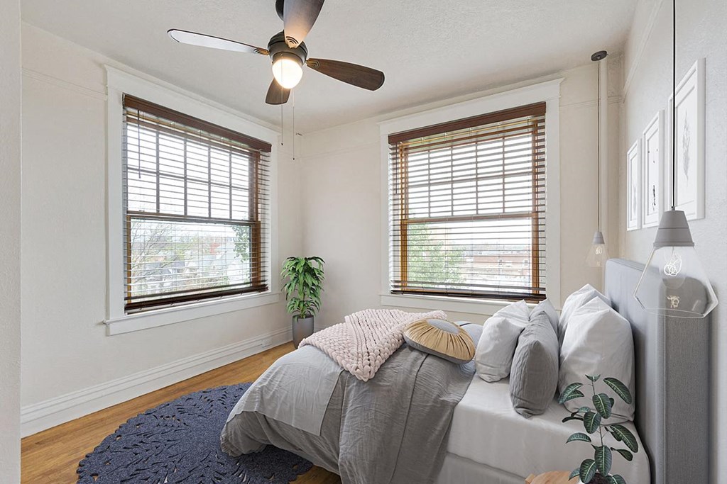 a bedroom with two windows and a ceiling fan