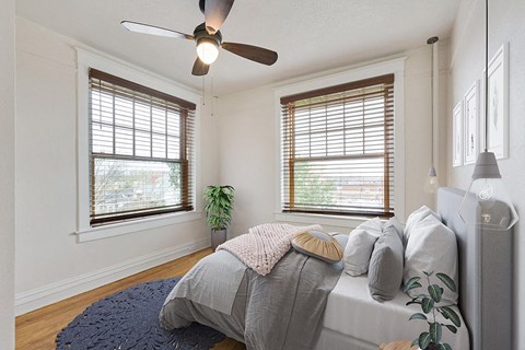 a bedroom with two windows and a ceiling fan
