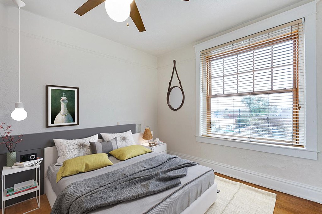 a bedroom with a large window and a ceiling fan