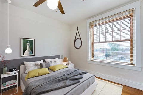 a bedroom with a large window and a ceiling fan