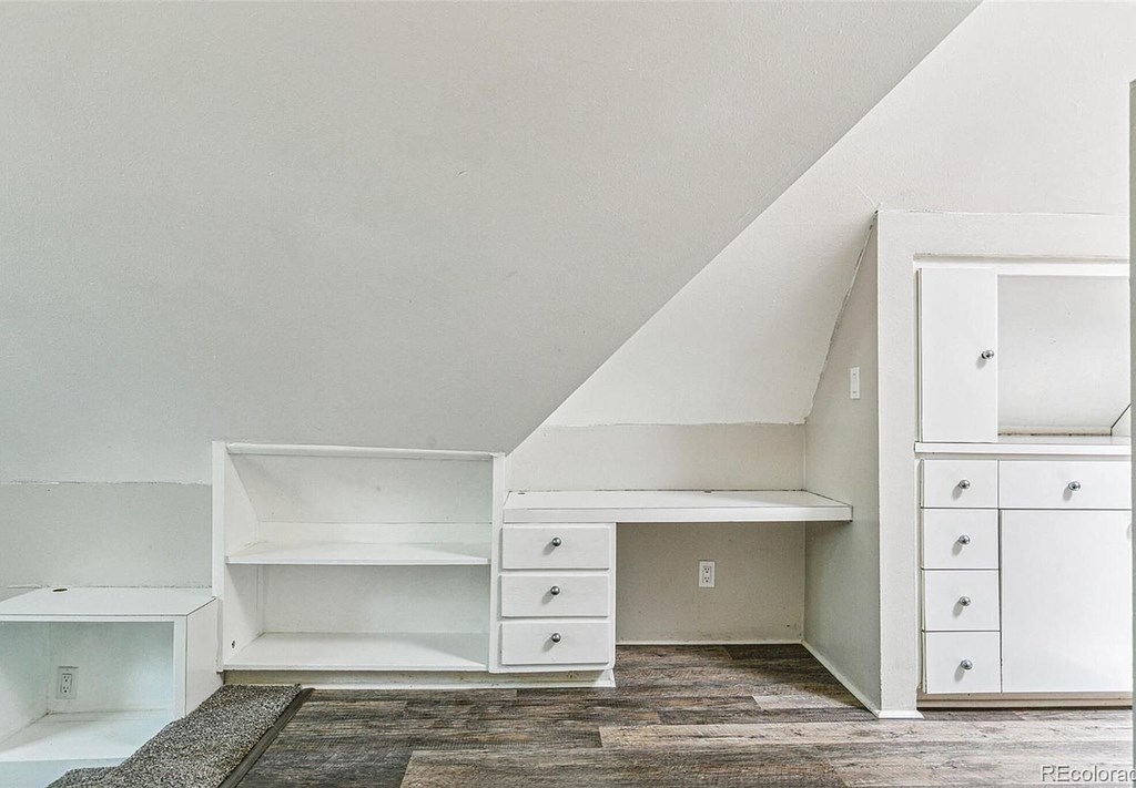 A white room with a desk and drawers.