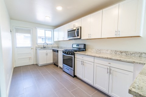 A kitchen with white cabinets and a granite countertop.