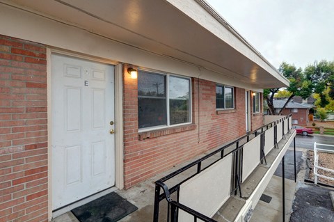 A red brick house with a white door and a black railing.