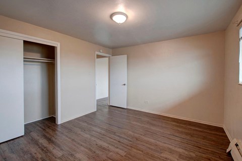 A room with a white door and a brown floor.