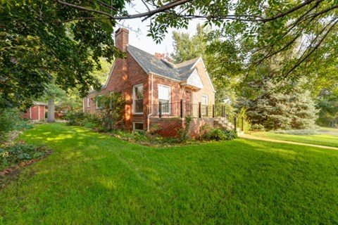 a small brick house with a porch and a grass yard