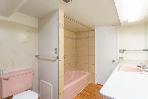 a bathroom with a pink tub and a sink and a toilet