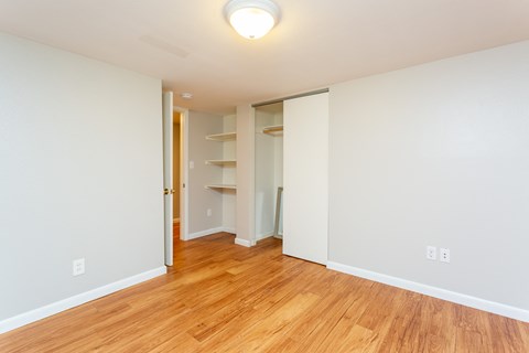 an empty living room with wood flooring and a closet