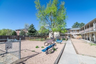 A playground with a blue swing set and a fence.