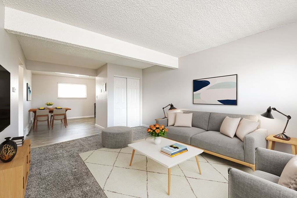 A living room with a grey couch, a white coffee table, and a painting on the wall.