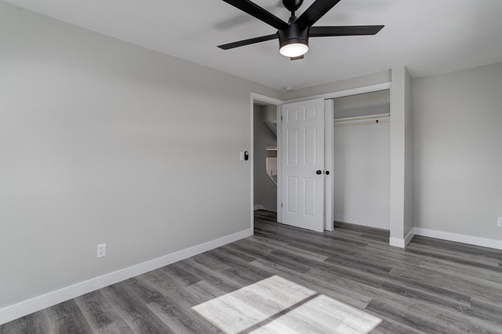 an empty living room with a ceiling fan and a door to a hallway
