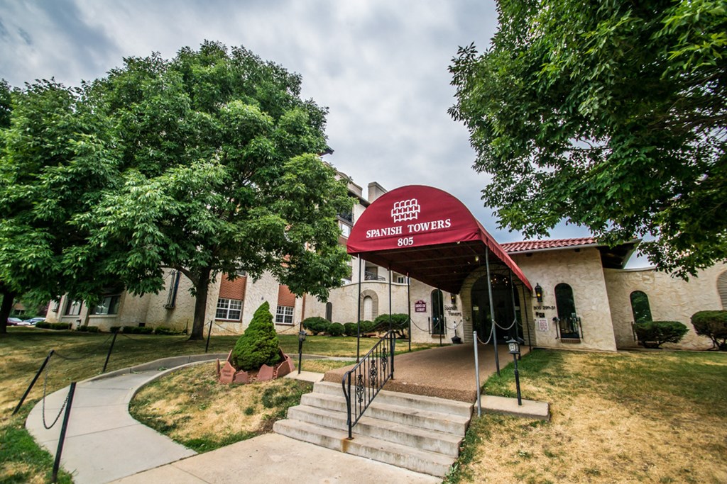 the front of a building with stairs and a red awning