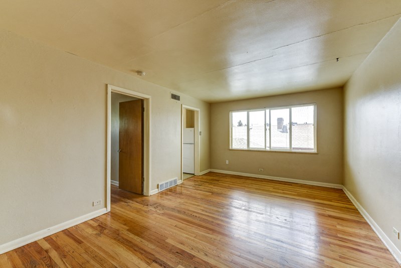 the living room of an empty house with wood floors and a window