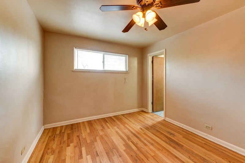 the living room of an empty house with a ceiling fan and wood floors