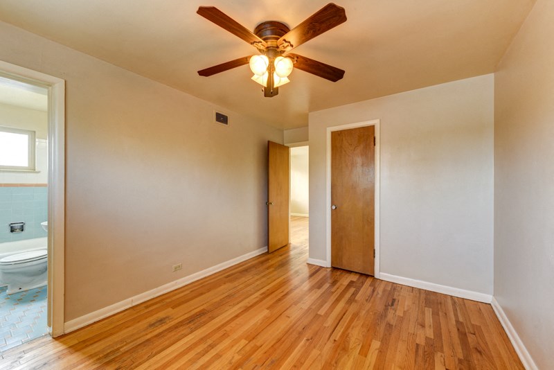 an empty living room with wooden floors and a ceiling fan
