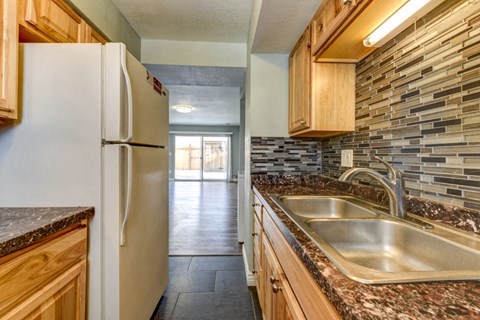 A kitchen with a white refrigerator and a granite counter top.