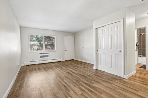 A room with a white door and a window with a view of a street.