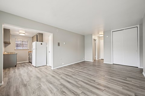 A spacious room with a white fridge and wooden flooring.