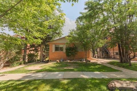 A house with a green lawn and trees in front.