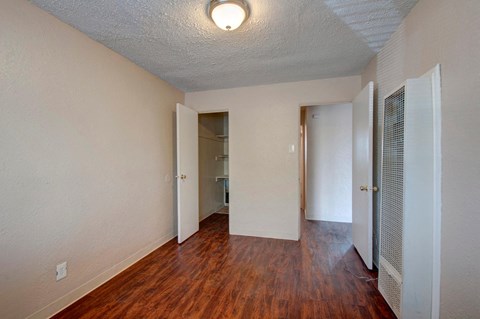 an empty living room with hard wood flooring and a closet